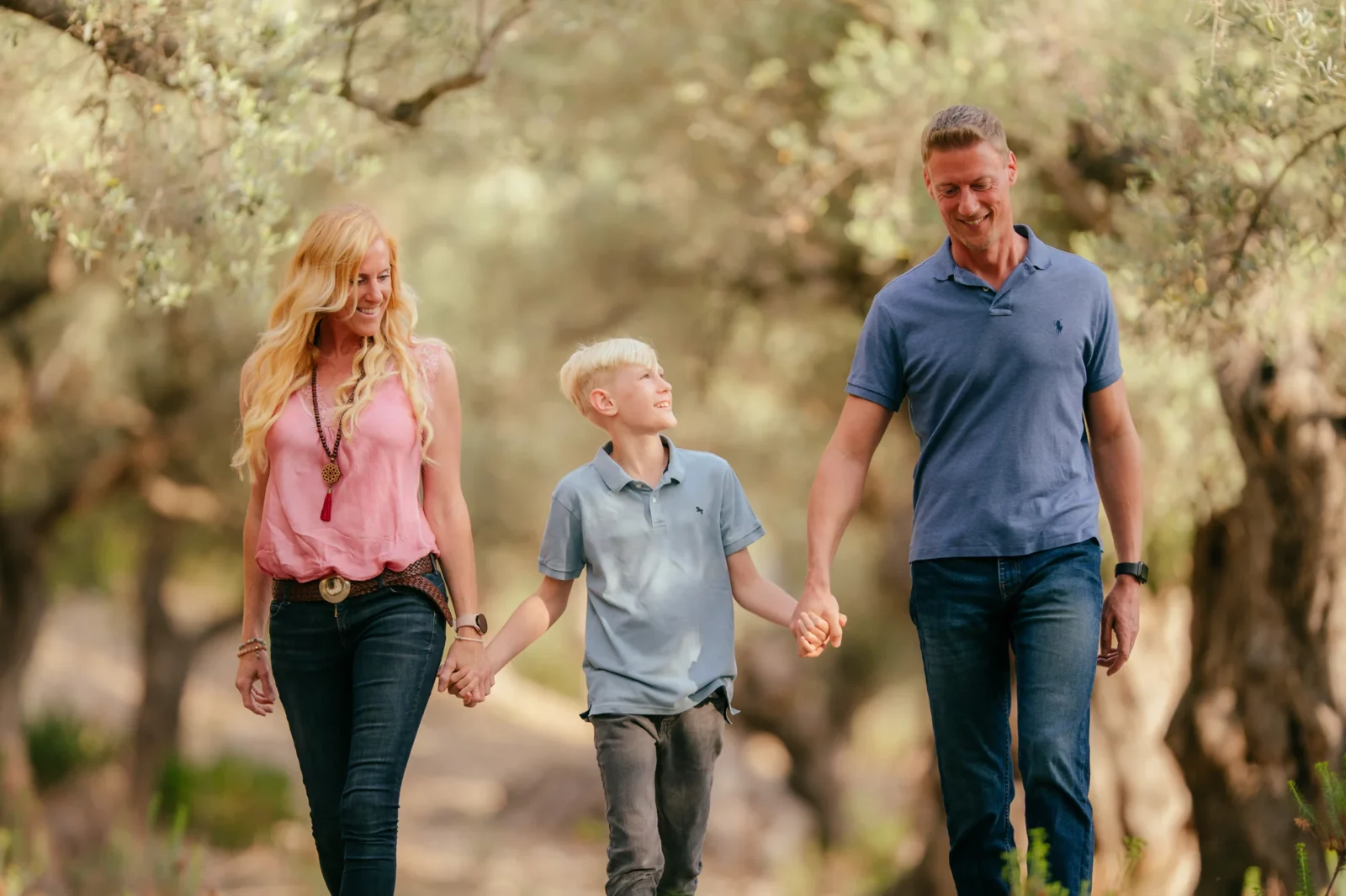 Familie geht Hand in Hand durch einen Olivenhain auf Mallorca