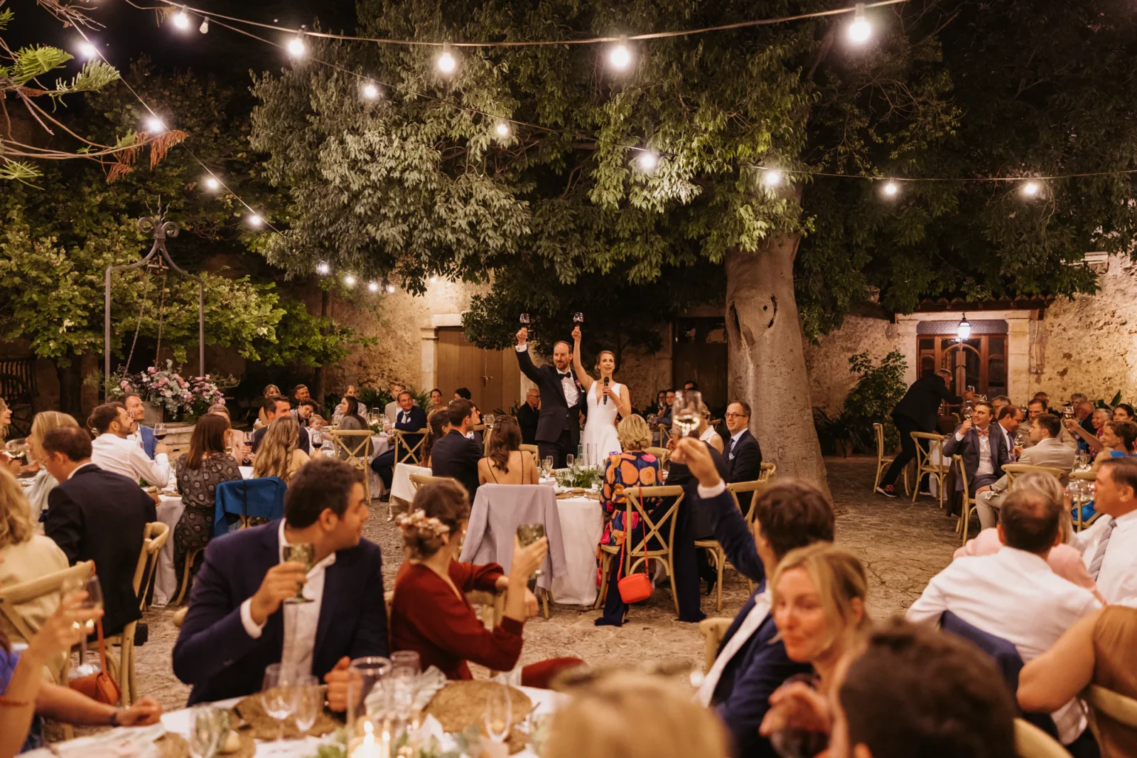 Abend im Innenhof einer Finca unter Lichterketten, Gäste an den Tischen